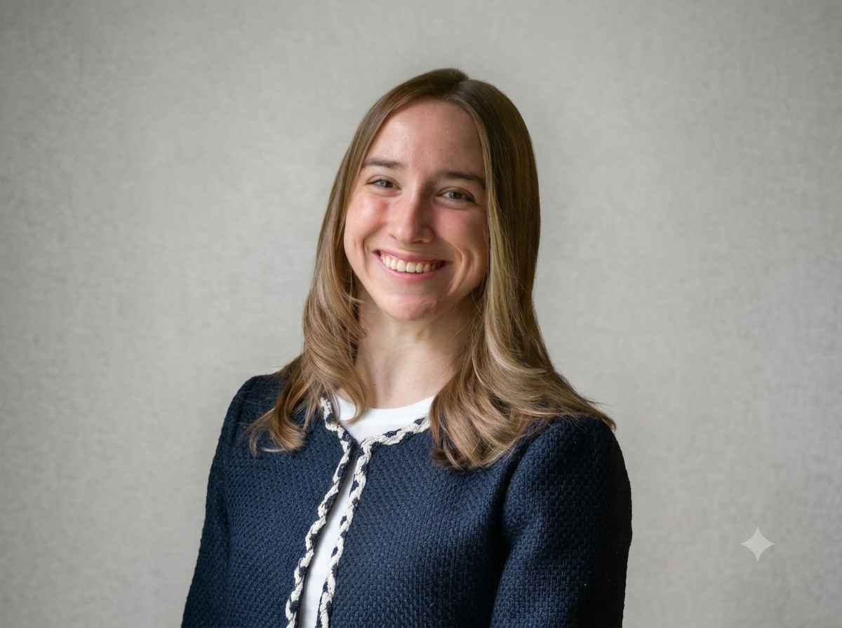 A white woman with brunette hair wearing a navy blue blazer. 