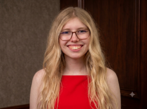 a white woman with blonde hair and glasses wearing a red dress